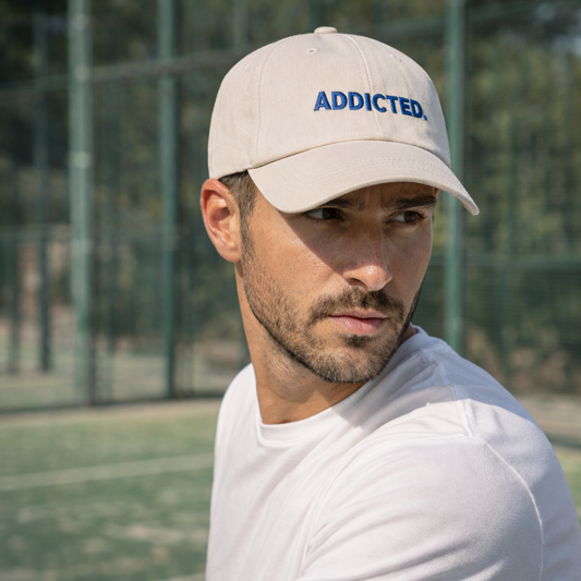 Man wearing a beige cap with 'ADDICTED' text on a sports court