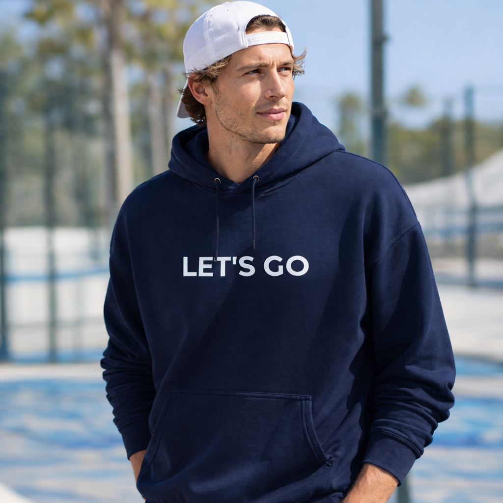 Man wearing a navy hoodie with 'LET'S GO' text outdoors.