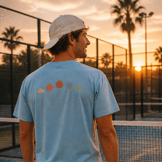 Person on a padel court holding a padel ball with a sunset in the background