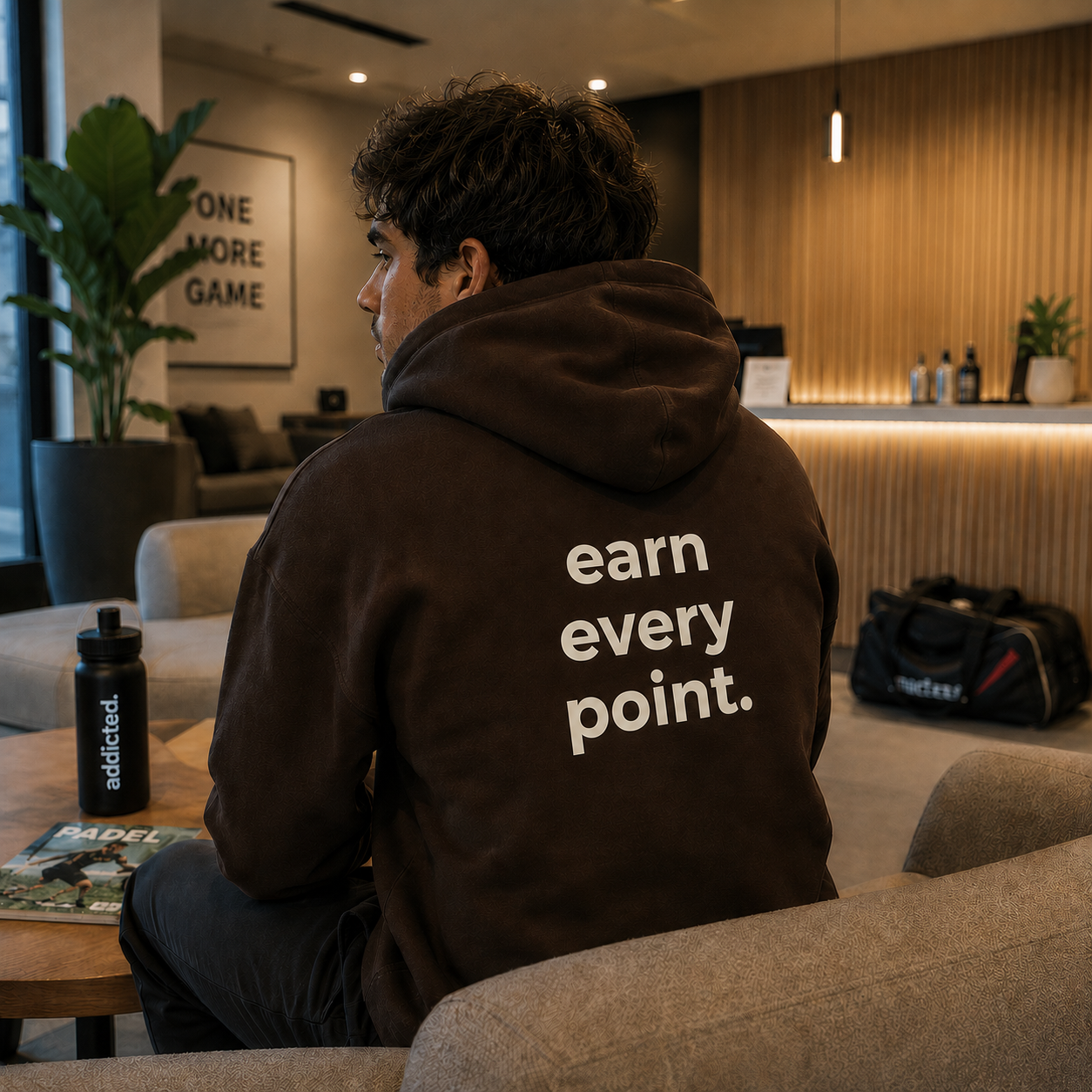 Person wearing a hoodie with 'earn every point' text in a modern indoor setting.